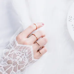 Minimalistische ultradünne Ringe aus Roségold-Titanstahl auf weißem Spitzen-Hintergrund