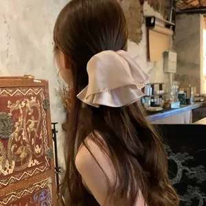Rückansicht eines eleganten Satin-Haargummis mit Perlen an einem asiatischen Model