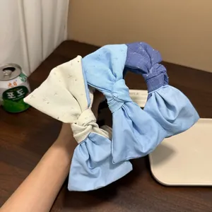 Dettaglio di cerchietti con fiocchi fatti a mano e strass scintillanti in blu e crema