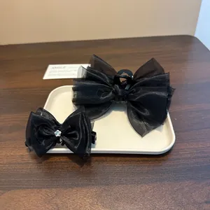 Elegant detailed view of two black organza bow hair clips displayed on a white tray