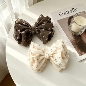 Close-up detail of elegant floral chiffon bow hair clips in brown and cream colors