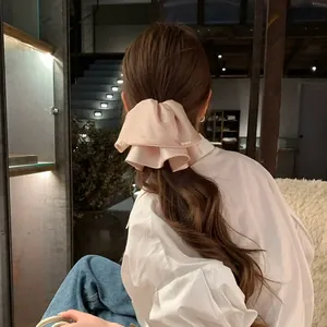 Detail eines rosa Satin-Rüschen-Haarclips mit Perlen auf langem, gewelltem Haar