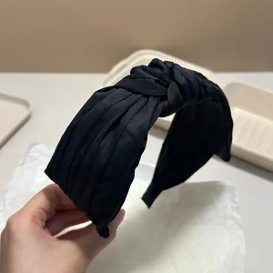 Detailed view of an elegant black pleated knotted headband with a retro high-end texture