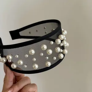 Dettaglio di un elegante cerchietto in rete nera decorato con perle finte bianche