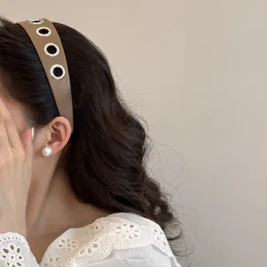 Dettaglio ravvicinato del cerchietto in pelle marrone stile punk con occhielli in metallo