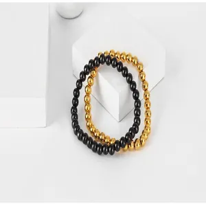 Close-up of handmade gold and black titanium steel beaded bracelets on white props.