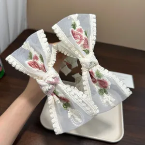 Nahaufnahme von elegantem weißem besticktem Spitzen-Haarreif mit rosa Blumenmustern