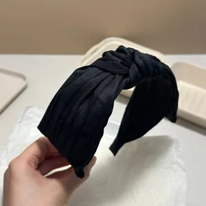 Close-up of black pleated knotted headband showing fabric texture and design