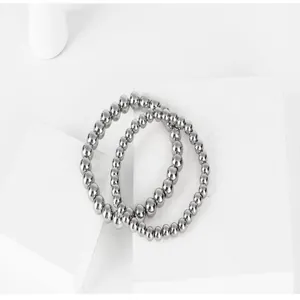 Macro view of polished silver titanium steel beaded bracelets on white geometric stand