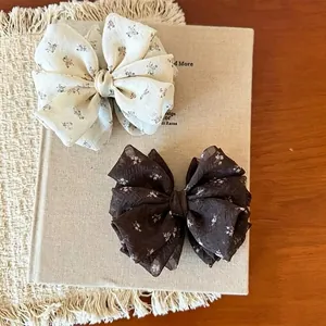 Detailed view of elegant floral bow banana clips in cream and dark brown chiffon.