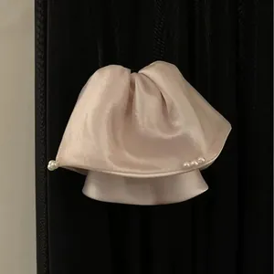 Detailansicht einer eleganten Haarklammer aus champagnerfarbenem Satin mit Perlenakzenten
