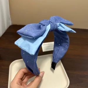 Dettaglio di un cerchietto a fiocco blu fatto a mano con motivo stellato e strati di raso.