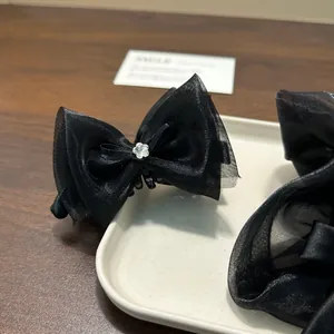 Close-up of elegant black mesh bow hair claw clip with floral rhinestone detail