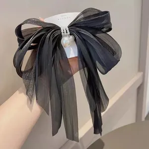 Primo piano dettagliato di un elegante fiocco per capelli nero con perle e cristalli.