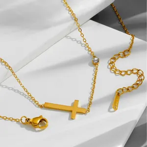 Détail du collier croix en acier inoxydable doré avec un accent en strass brillant.