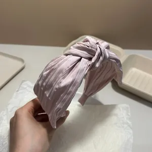 Close-up detail of a pink pleated knotted headband featuring an elegant high-top design