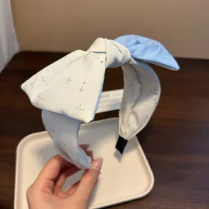 Dettaglio di un cerchietto in raso bianco e blu con delicati motivi a stella luccicanti.