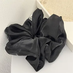 Gros plan d'un grand chouchou noir effet perlé montrant la texture du tissu