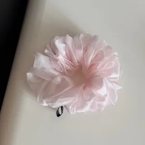 Détail d'un chouchou en organza rose pâle avec une texture plissée douce et légère