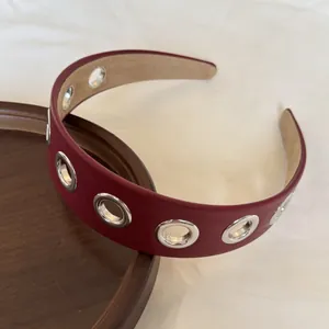 Vista dettagliata del cerchietto in pelle bordeaux stile punk con occhielli d'argento