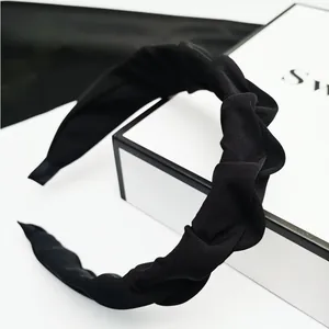 Nahaufnahme eines minimalistischen schwarzen plissierten Haarreifs mit weicher Stoffstruktur.