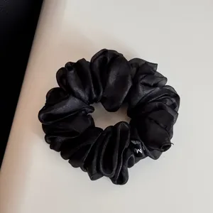 Vue détaillée d'un chouchou en organza noir avec une texture douce et froncée.