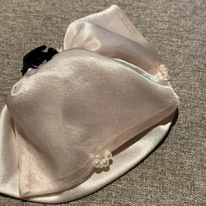 Nahaufnahme einer eleganten champagnerfarbenen Satin-Haarklammer mit Perlenakzenten