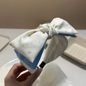 Dettaglio di un cerchietto con fiocco bianco e blu con delicati strass decorativi.