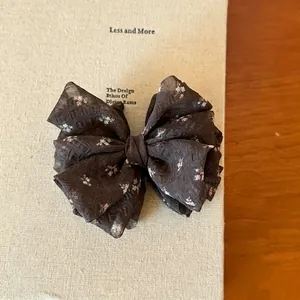 Close-up detail of a coffee brown floral print organza bow hair clip for elegant styling