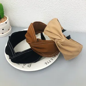 Dettaglio di tre cerchietti larghi con nodo a croce nei colori nero, marrone e beige