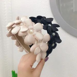Primo piano di eleganti cerchietti a fiori in tessuto con accenti di perle nero e rosa.