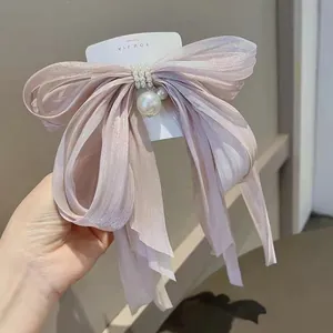 Dettaglio fermaglio a fiocco viola cangiante con perle e lunghi nastri decorativi