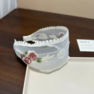 Detailansicht der exquisiten Blumenstickerei auf dem weißen Spitzenhaarband-Accessoire