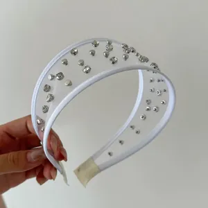 Dettaglio di un cerchietto in rete bianca con strass scintillanti e borchie argentate