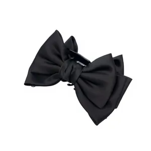 Détail d'une grande pince à cheveux avec un nœud en satin noir sur fond blanc