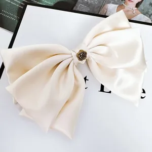 Detailansicht einer großen elfenbeinfarbenen Satinschleife mit Vintage-Metallrose
