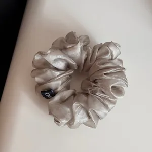 Vue détaillée d'un chouchou en organza champagne scintillant avec des volants chic