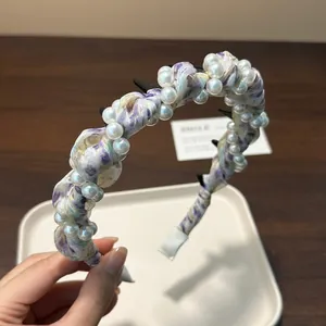 Detailed view of a purple floral pleated headband embellished with white pearls and clips