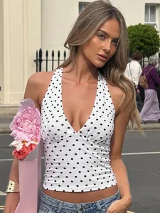 Detailed view of a white halter neck top with black polka dots on a fashion model.