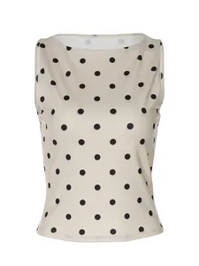 Detailweergave van een mouwloze slim-fit top met klassieke zwarte polkadots op crème.