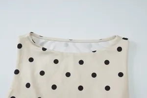 Gedetailleerd macrozicht op de boothals van een beige mouwloze top met zwarte stippen