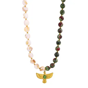 Close-up detail of a vintage golden eagle pendant on a Ruby Zoisite and shell bead necklace