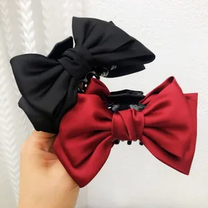 Détail de grandes pinces à cheveux avec nœuds en tissu noir et bordeaux élégant