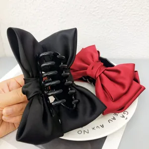 Vue détaillée de grandes pinces à cheveux en satin noir et rouge avec nœud papillon élégant