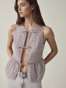 Detailansicht einer braun-weiß karierten Weste mit schicken Bändern und Ausschnitt-Design