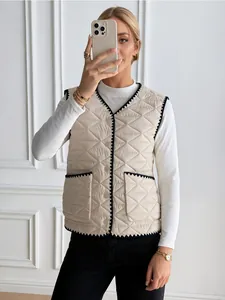 Detailed view of women beige quilted vest featuring navy sawtooth trim and snap buttons