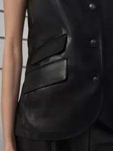 Detail view of black leather sleeveless vest showing texture and button flap pockets