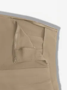 Detailansicht des verdeckten Seitenreißverschlusses an khakifarbenen Anzughosen.