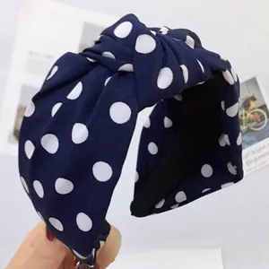 Dettaglio del cerchietto in tessuto blu scuro a pois bianchi con nodo centrale