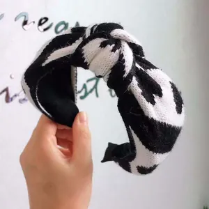 Close-up of black and white knitted headband featuring a stylish and cozy top knot design